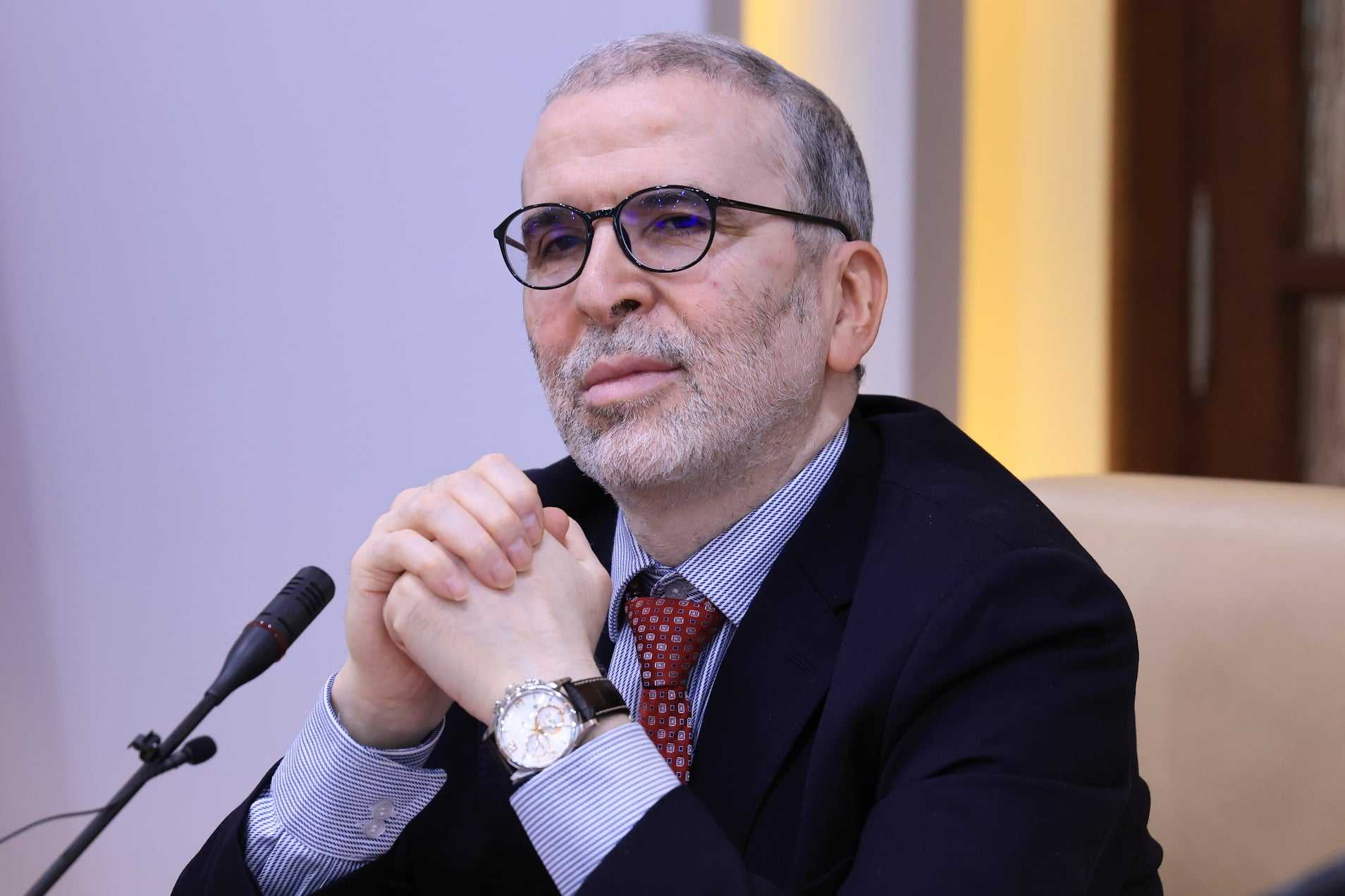 قد تكون صورة لـ شخص واحد، لحية، جلوس، نظارة وساعة يد